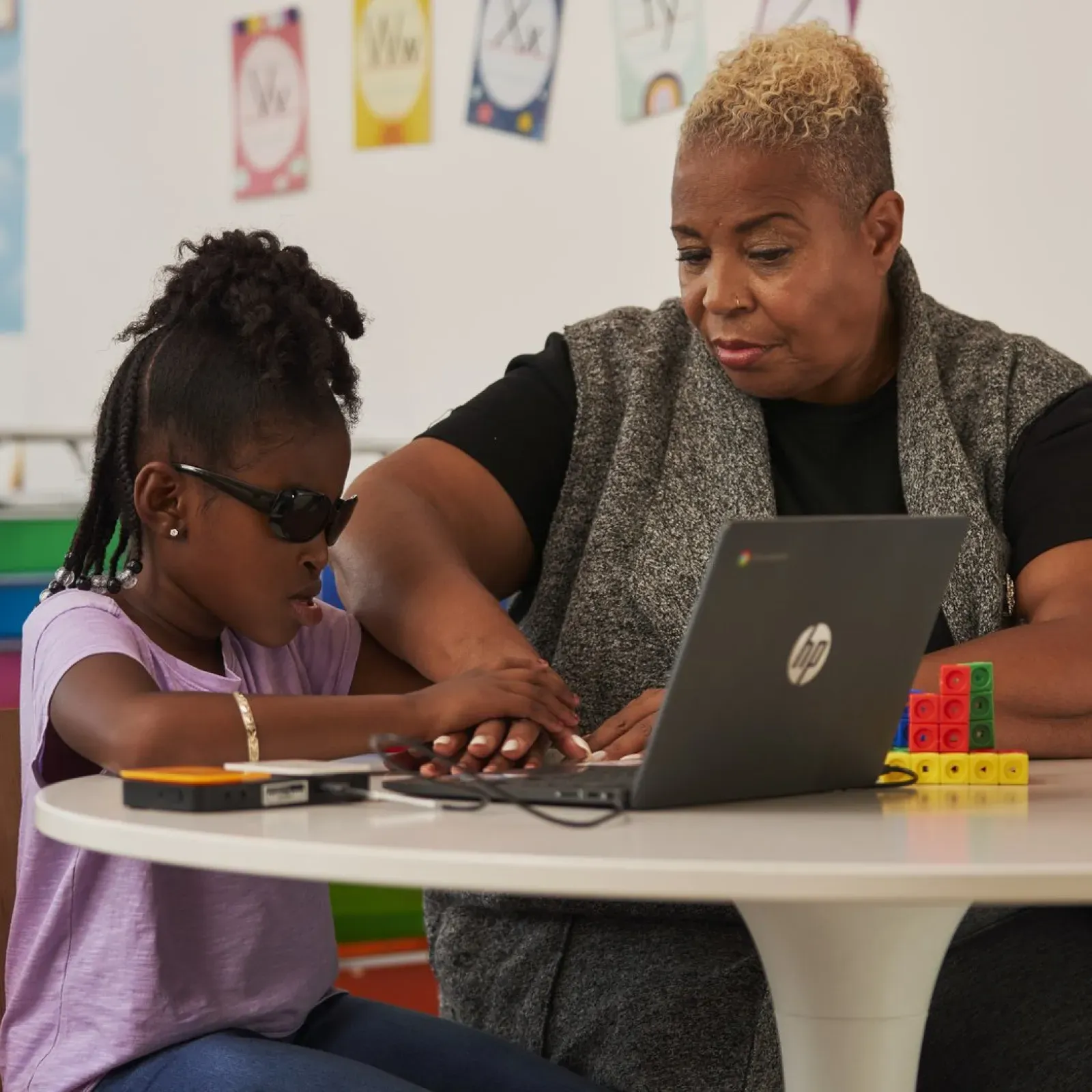 A teacher helping her blind student working on a Google Chromebook